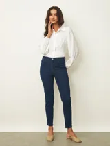 Jean de corte skinny en color azul medio, con tiro medio, cierre frontal con botón y bolsillos laterales y traseros.