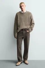 Bota de piel con acabado serraje color beige, con detalle de arnés y hebilla lateral. Presenta horma en punta y suela a contraste con ligero tacón.