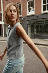 Chaleco de punto suave con cuello redondo, diseño sin mangas y cierre frontal con botones. Presenta terminaciones en rib en el cuello, sisas y ruedo.