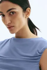 Top ajustado de punto suave, color azul grisáceo, con escote bote, manga japonesa y fruncidos laterales que crean un efecto drapeado frontal.