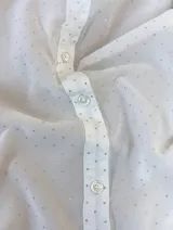 Camisa de corte recto y diseño traslúcido con sutiles destellos brillantes, cuello clásico, cierre frontal de botones y mangas largas con puños abotonados.