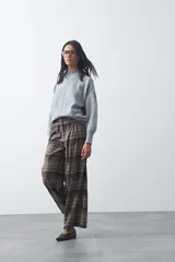 Polera de tejido de punto color gris, con cuello alto, mangas largas abullonadas con puños elásticos y costura central vertical en el frente. Presenta una abertura sutil en la espalda.