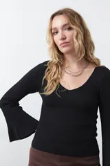 Top de tejido acanalado negro, con escote en V, mangas largas con terminación acampanada y ajuste al cuerpo.