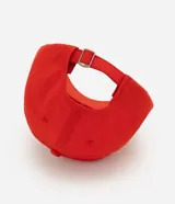 Gorra roja confeccionada en sarga de algodón, con visera curva y bordado frontal en tono claro con la inscripción "Saint Tropez South France" y un escudo. Cuenta con ojalillos de ventilación y ajuste posterior.