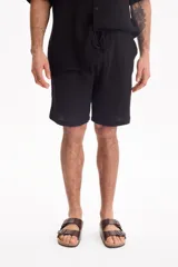 Bermuda negra de muselina con corte baggy, estilo deportivo y cordón ajustable en la cintura.