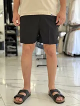 Short de baño gris liso, con diseño clásico y un pequeño parche circular con logo en la parte inferior de la pierna izquierda.
