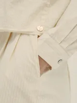 Shorts celestes a rayas verticales, de tiro alto y corte holgado, con pinzas en el frente y detalle de Polonio en cobre.