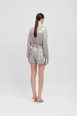 Camisa de manga larga color plateado con lentejuelas. Presenta cuello y puños de satén en tono gris claro, y dos bolsillos de parche frontales con solapa de satén.