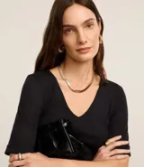 Blusa femenina de corte ajustado confeccionada en tejido rib acanalado, con escote en V y mangas cortas con dobladillo plegado.