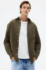 Camisa de algodón Oxford con cuello americano, tapeta clásica, bolsillo superior abierto y canesú en la espalda. Mangas largas con puños abotonados y bajo levemente redondeado.