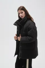 Campera puffer negra de corte holgado, con cuello alto, cierre frontal oculto y bolsillos laterales.