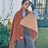 Bufanda reversible de lana, con un lado en color terracota y el otro en beige, con flecos en los extremos.