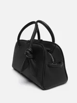 Cartera tipo bowling de cuero granulado negro, con asas superiores, correa ajustable y extraíble, y detalle de lazo en el lateral.