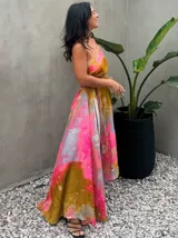 Vestido largo verde con diseño estampado tipo tie-dye y detalles dorados, de corte fluido, un solo hombro y diseño amplio.
