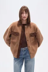 Campera tipo shacket de corderito color crema, con detalles en pana marrón en cuello, solapa de botones y bolsillos frontales. Diseño holgado de manga larga con cierre frontal de botones.