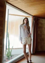 Blusa de poliéster con estampado de rayas, cuello con pañuelo integrado y detalle de abertura en V, de corte recto y mangas largas abullonadas con volantes.