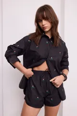 Short negro de algodón con bordados de pequeñas flores rosas y verdes, cuenta con cintura elástica y cordón ajustable.