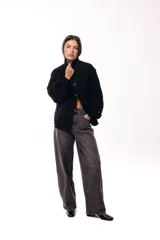 Campera de jean negra con mangas largas tejidas en crochet con diseño calado y detalles florales en relieve. Presenta cuello camisero, cierre frontal y bolsillos en el pecho.