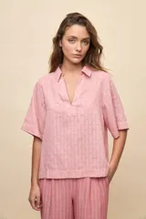 Blusa celeste de manga corta con cuello camisero y escote en V, confeccionada en tejido liviano con textura sutil y estampado de lunares.
