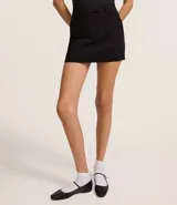 Short pollera confeccionado en bengalina color blanco, de cintura alta con trabillas y cierre frontal.