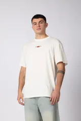 Remera blanca de corte regular, cuello redondo y manga corta, con pequeño estampado alusivo en el centro del pecho.