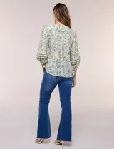 Blusa holgada de gasa estampada en tonos amarillos y azules, con cuello en V, mangas 3/4 abullonadas y alforzas horizontales.