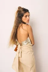 Falda midi color beige de tiro alto y silueta envolvente, con lazo ancho para anudar en la cintura, diseño asimétrico y terminación de flecos largos en el ruedo.