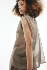 Pantalón de punto fino color beige, de corte recto y holgado, con cintura elástica y una falda pareo superpuesta con nudo lateral.