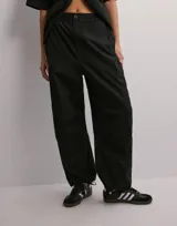 Pantalón cargo negro de popelina de algodón, con corte holgado, cintura ajustable y múltiples bolsillos laterales y traseros.