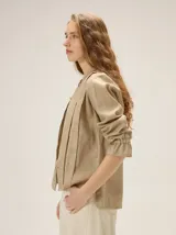 Camisa de lino color crudo, con cuello mao y cierre frontal con botones. Cuenta con detalles de alforzas verticales y diseño bordado floral en el frente, además de mangas 3/4 con volumen y puños elásticos.