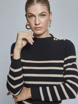 Sweater de punto a rayas horizontales en color negro y beige, con cuello alto y detalle de botones dorados en el hombro izquierdo. De manga larga y ajuste al cuerpo.