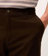 Bermuda masculina slim confeccionada en sarga de algodón con elastano, color beige, con bolsillos laterales tipo chino, bolsillos traseros embutidos con botón, trabillas en la cintura y cierre frontal con botón y cremallera.