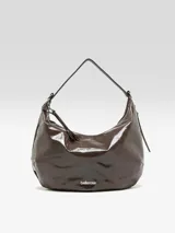 Bolso tipo hobo de diseño media luna, confeccionado en cuero caprino con acabado charol y textura grabada. Cuenta con cierre superior de cremallera, asa ajustable y el logo de la marca en la parte frontal.