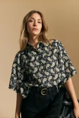 Camisa de manga corta con cuello camisero, confeccionada en tela estampada con diseño paisley en tonos negro, beige y azul.