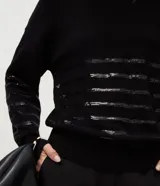 Suéter de punto color negro con cuello redondo y mangas largas. Presenta un diseño con franjas horizontales decoradas con lentejuelas del mismo tono en el cuerpo y las mangas.