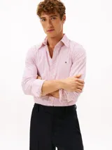 Camisa de manga larga Tommy Hilfiger de corte regular, confeccionada en popelín de algodón blanco con diseño de rayas verticales rojas. Cuenta con cuello clásico, cierre frontal de botones y el logo de la marca bordado en el pecho.