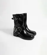 Bota corta de estilo biker, color negro, con taco cuadrado bajo y suela track. Presenta correas con hebillas metálicas plateadas y argollas decorativas en la zona del tobillo y en la parte superior de la caña.