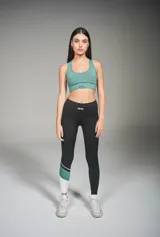 Calza deportiva larga negra con recortes en blanco y verde en la parte inferior de una pierna.