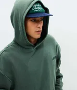 Hoodie de algodón verde con efecto acid wash, corte boxy, capucha y gran bordado en relieve con la palabra "horizon" en la espalda.