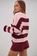 Sweater de tejido de punto con diseño de rayas horizontales anchas en color rosa y bordó, de corte holgado, cuello redondo y mangas largas.