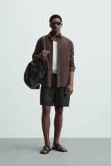 Bermuda de lino color blanco hueso, de corte relajado y tiro medio. Presenta cintura elástica ajustable con cordón, pliegues frontales y bolsillos laterales y trasero.