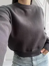 Sweater gris oscuro de corte cropped, con cuello redondo y mangas largas.