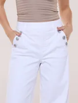 Pantalón de denim blanco de tiro alto y corte wide leg, con bolsillos diagonales decorados con botones metálicos a los lados y piernas de caída recta.