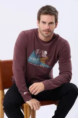 Remera de manga larga color bordó, con cuello redondo y estampado frontal de un paisaje montañoso con pinos y la palabra "LEGACY".