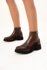 Bota de cuero color chocolate con caña al tobillo y cierre lateral. Presenta una combinación de texturas en el cuero y una suela chunky dentada de color negro.