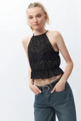 Top blanco sin mangas con cuello halter, bordado con calados y elástico con volado en la cintura.