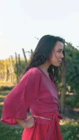 Top cruzado de muselina con diseño bicolor en tonos fucsia y rojo, de manga corta amplia y lazo ajustable en la cintura.