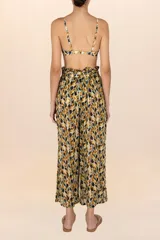 Pantalón largo de tejido ligero y traslúcido con estampado de hojas en tonos mostaza, marrón y negro. Presenta cintura elástica con lazo ajustable y corte recto.