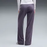 Pantalón calza deportiva Puma de corte ancho, color violeta, con cintura alta elástica y logo pequeño impreso en la pierna izquierda.