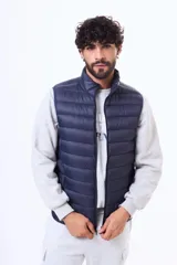 Chaleco acolchado tipo puffer, color azul marino, con cuello alto y cierre frontal completo.